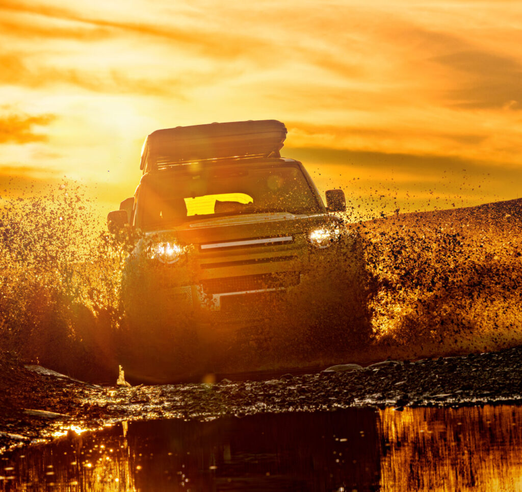 SUV driving through muddy terrain with durable automotive accessories designed for Alberta driving conditions